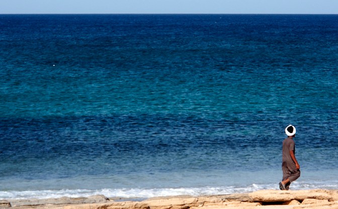 Boy walking along the sea shore.