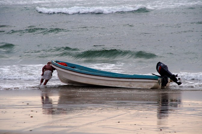 Turning the boat into the waves by putting his back into it.